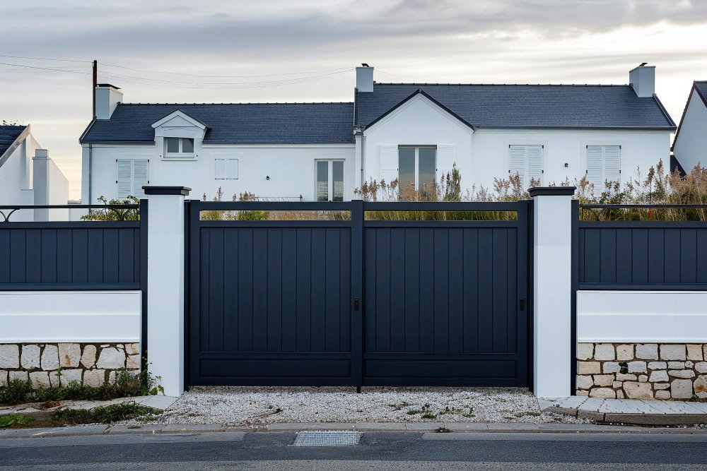 Portail aluminium battant noir avec piliers maçonnés devant une maison dans les Yvelines